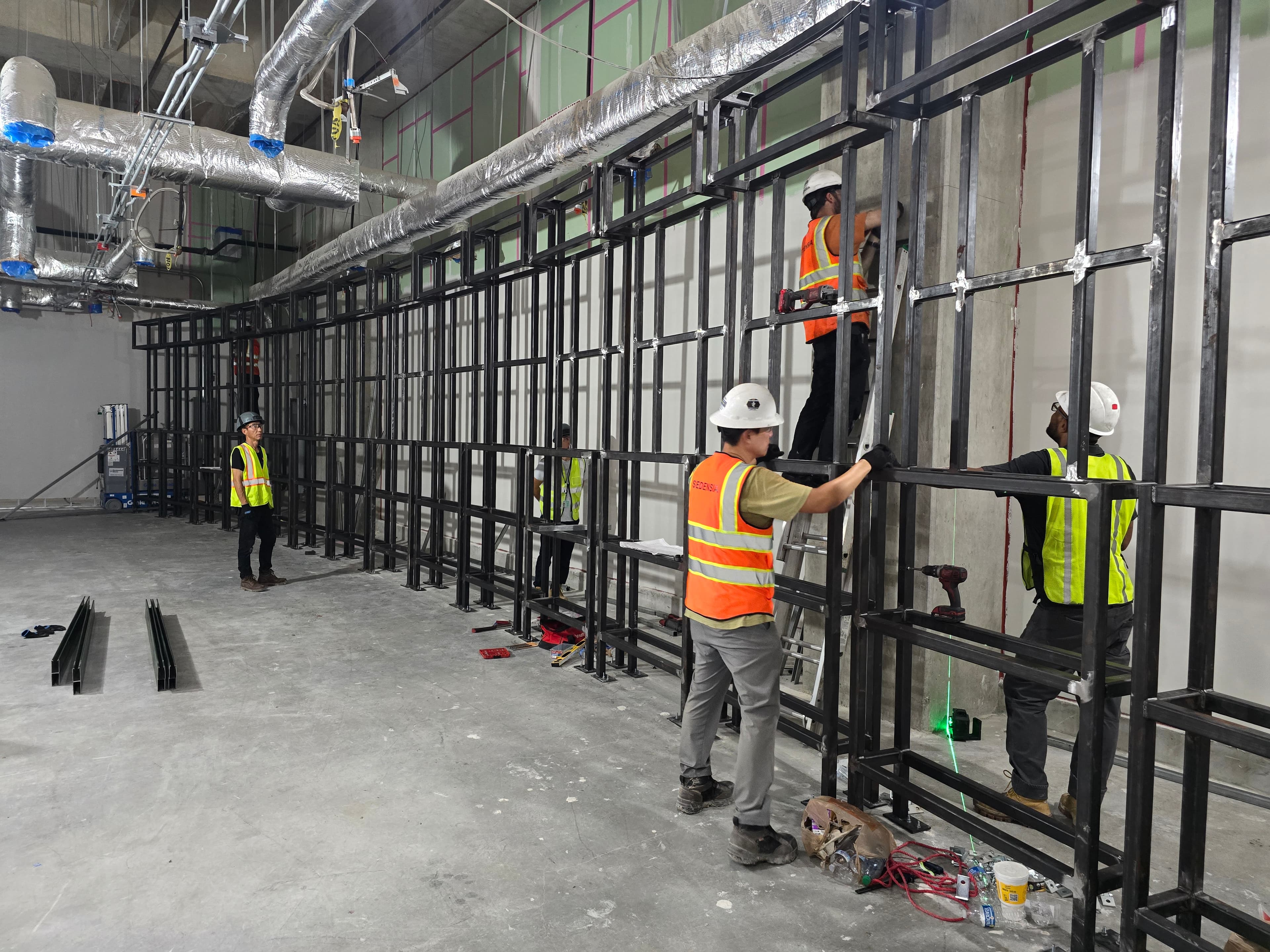 Crew in hard hats and safety vests assembling a steel mounting frame