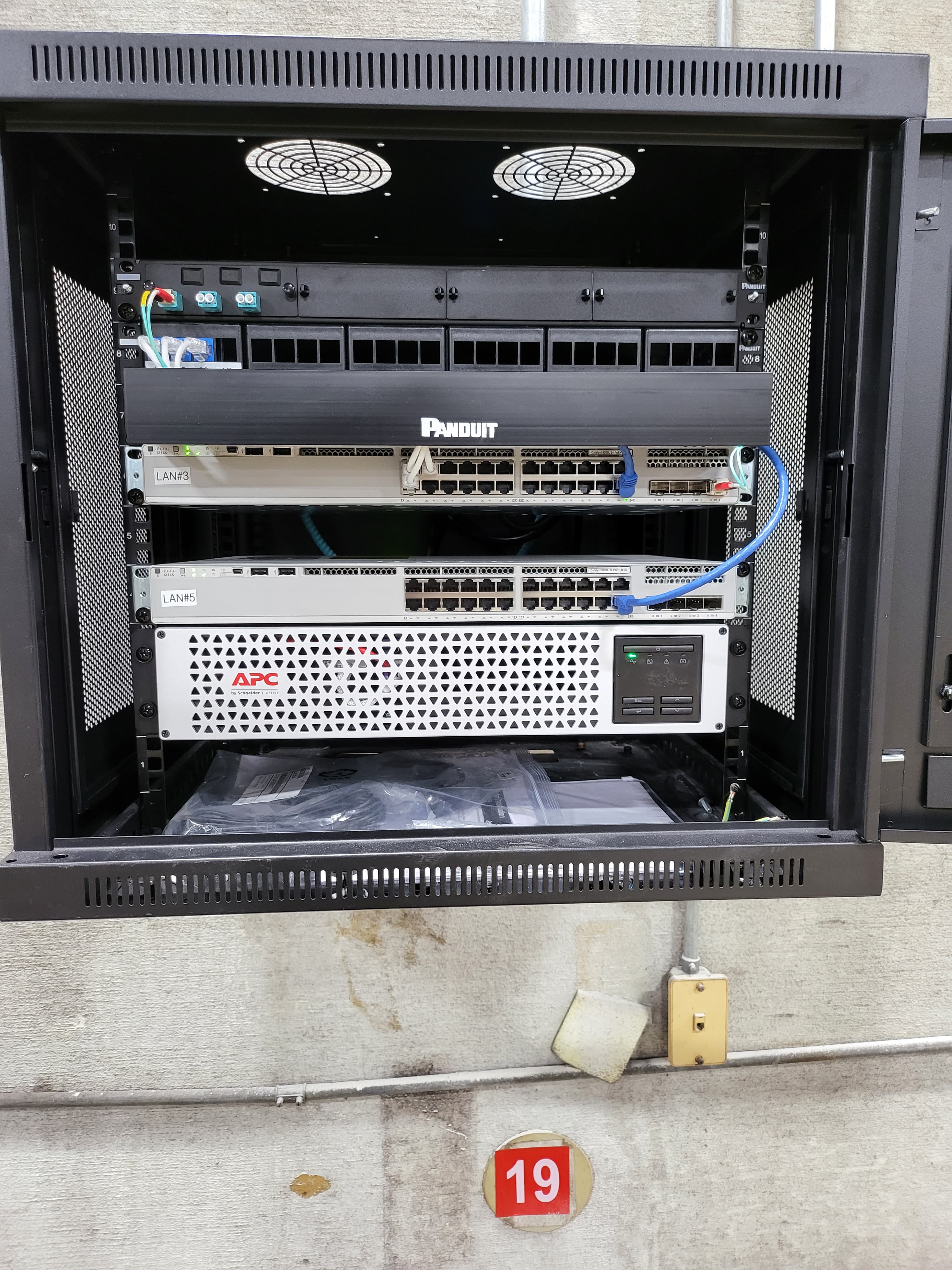 Wall-mount IDF cabinet with network switches and UPS during installation
