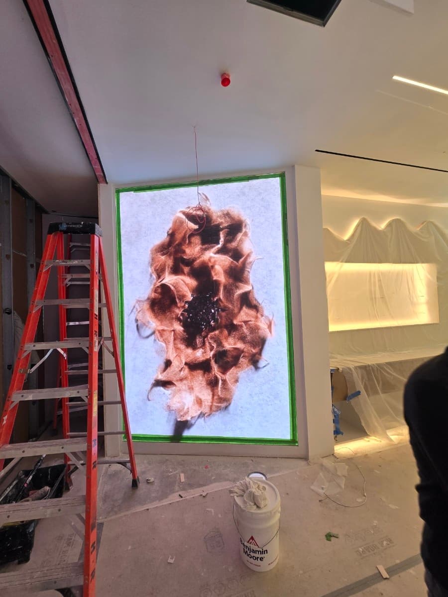 Technician finishing a fine-pitch LED video wall inside a retail space